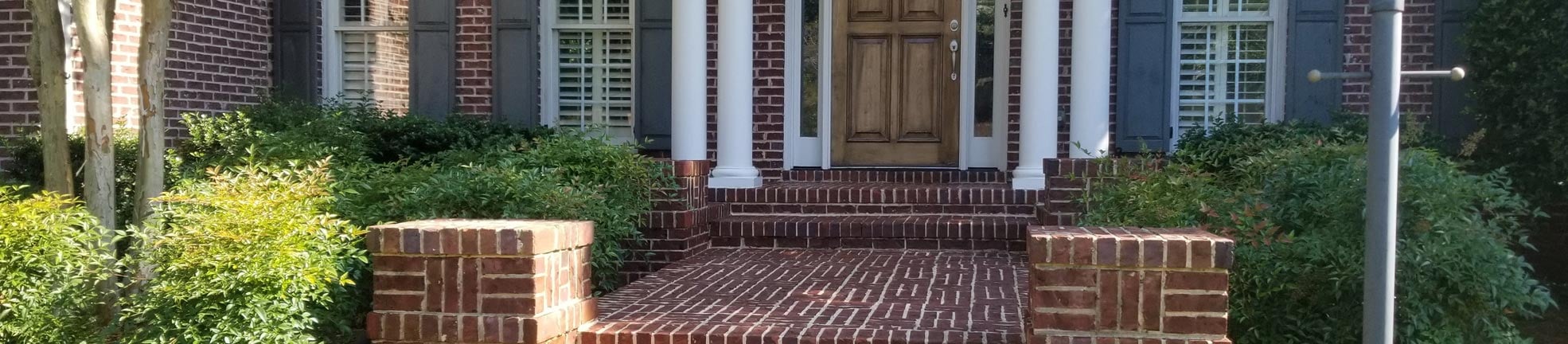 Crew member pressure washing the siding of a two-story house, with an Alpha Pressure Washing truck in the driveway (2018)