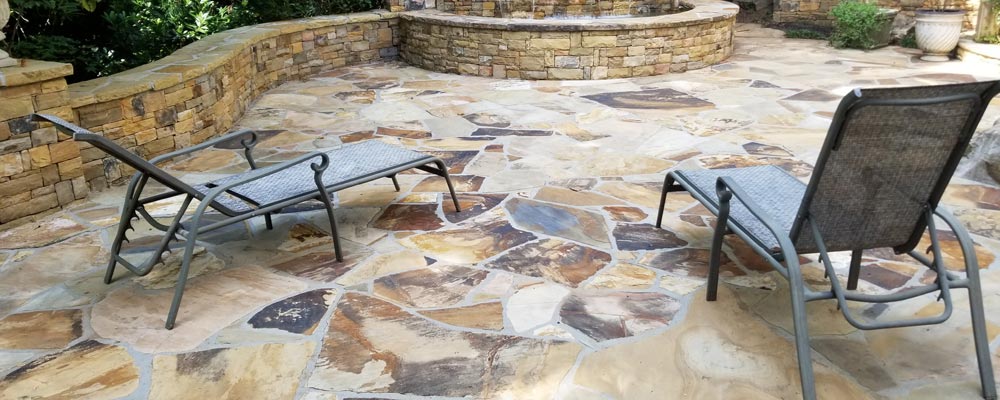 Flagstone patio after pressure washing, with a garden bench and grill at the edge (2018)