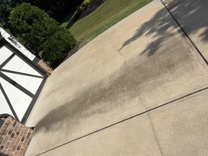 Concrete driveway before pressure washing in Canton, GA showing a heavy streak of black algae and organic staining down the center