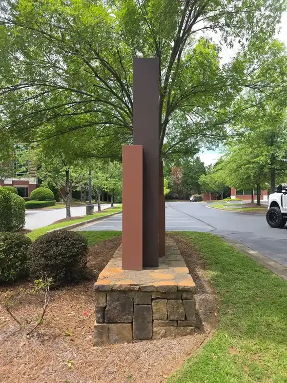 Wide view of a tall commercial monument sign on a stone base after soft washing in Duluth, GA, surrounded by trees.