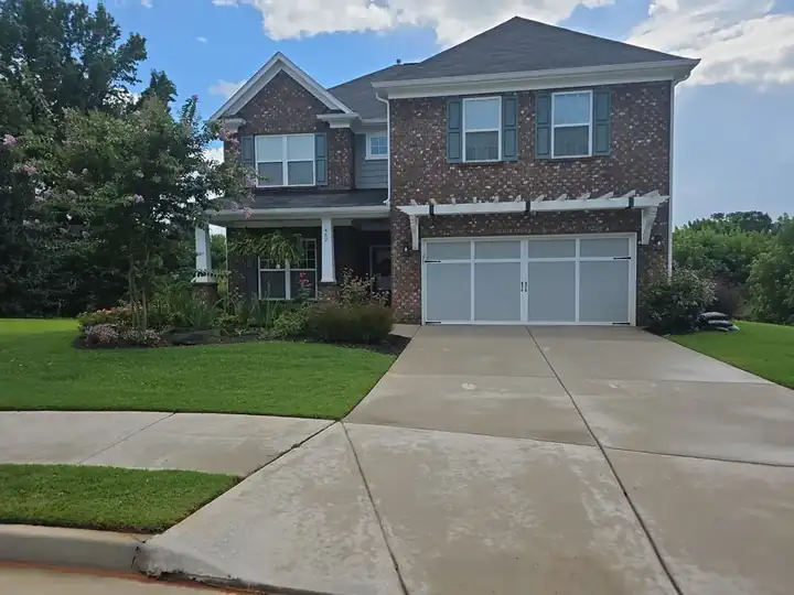 Full view of a concrete driveway leading to a two-story brick home in Canton, GA after pressure washing.