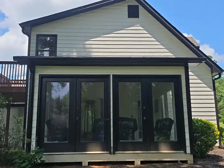 White vinyl siding and large glass doors on the rear of a residential home in Canton, GA after house washing.