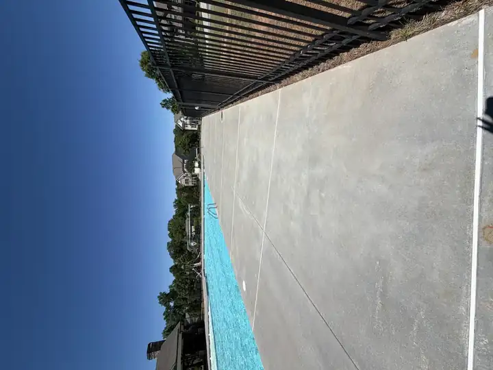 Long section of concrete pool deck pressure-washed beside community pool in Canton, GA, clean and even