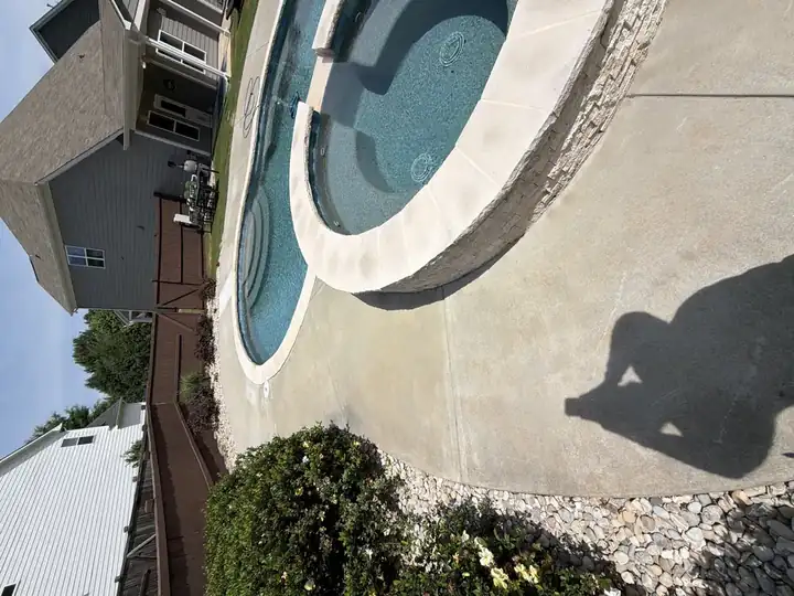 Clean concrete pool deck and elevated spa after pressure washing in Canton, GA, natural stone coping gleaming