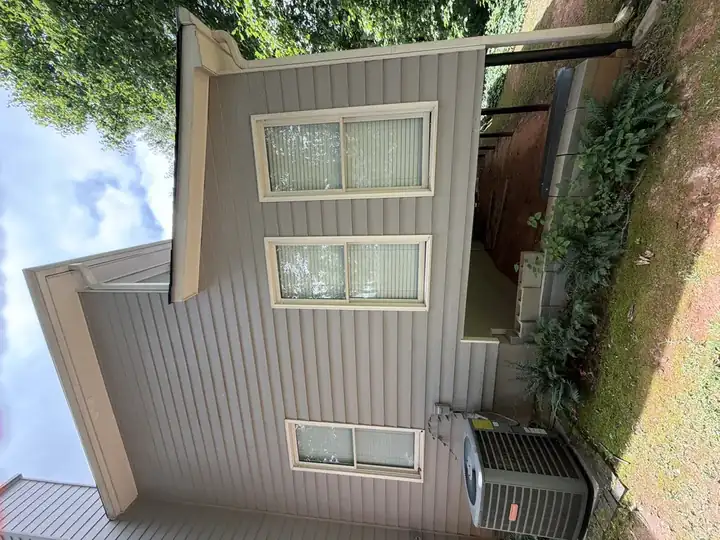 Clean gray vinyl siding on side gable end of Canton, GA home with three windows after house washing service