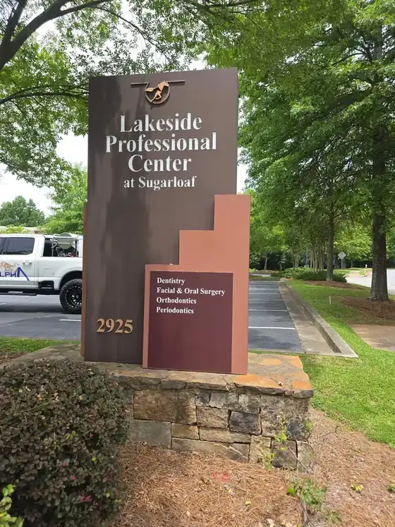 Commercial monument sign on a clean stone base after soft washing in Duluth, GA, with the Alpha Pressure Washing service truck parked nearby.