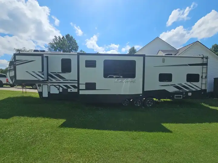White Fuzion Impact Edition fifth-wheel RV parked on a grass lawn beside a residential home in Canton, GA.