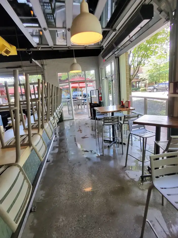 Wet concrete floor inside a commercial restaurant space with chairs stacked along the wall during a degreasing job in Alpharetta, GA.