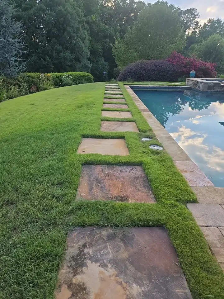 Stone stepping-stone path along the edge of a backyard pool at a residential property in Milton, GA.