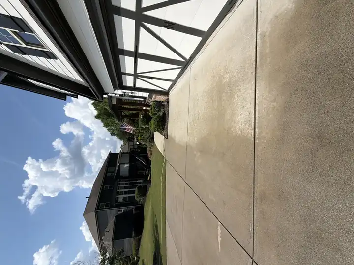 Side view of clean concrete driveway after pressure washing in Canton, GA, garage doors and landscaping visible under blue sky