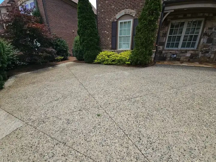 Wide exposed aggregate concrete driveway in front of a brick home in Marietta, GA.