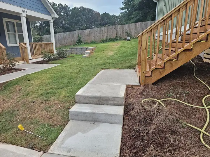 Concrete steps and walkway beside a wood deck staircase at a new construction pressure washing job in Atlanta, GA.