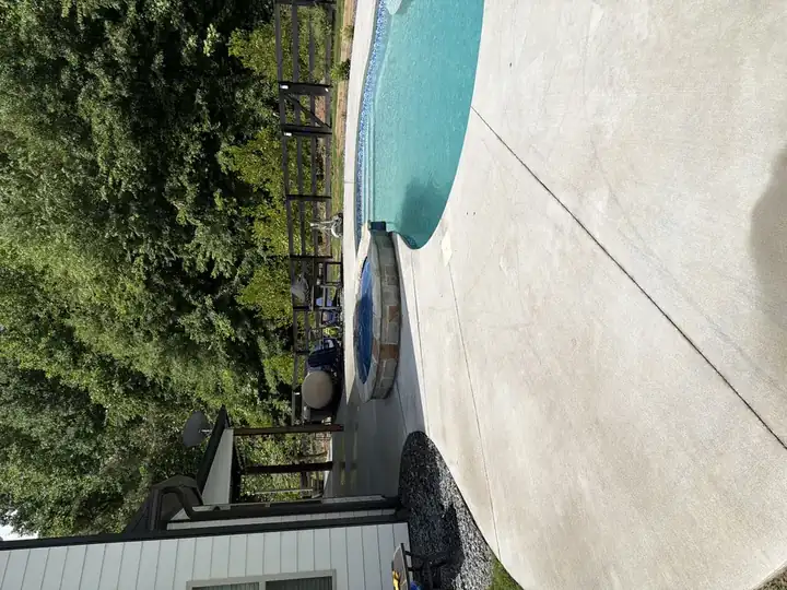 Clean concrete pool and spa deck after pressure washing in Canton, GA, wide view showing the full curved surround and backyard