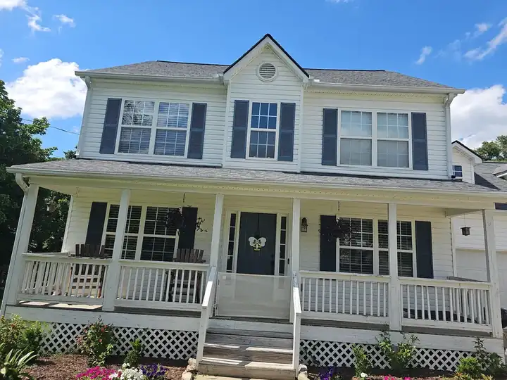 Front of a two-story home with white vinyl siding, covered porch, dark shutters, and asphalt-shingle roof in Canton, GA.