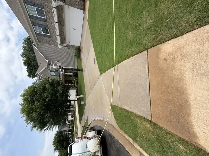 Concrete driveway and walkway cleaned by pressure washing in Canton, GA, service truck departing at left