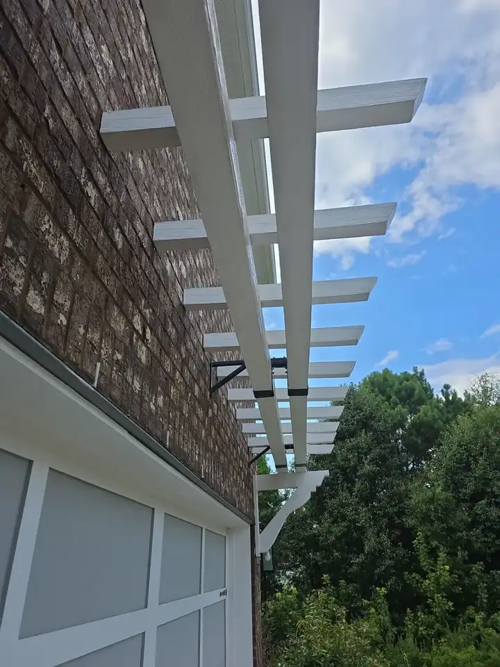 Underside of a white wood pergola attached to a brick wall at a pressure washing job in Canton, GA.