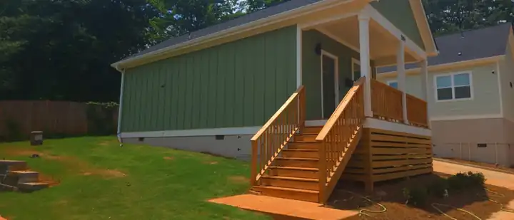 Green board-and-batten siding on a new construction home with wood front porch steps at a pressure washing job in Atlanta, GA.