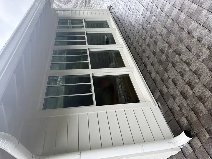 Clean white vinyl siding and large porch windows after house washing service on a Marietta, GA home