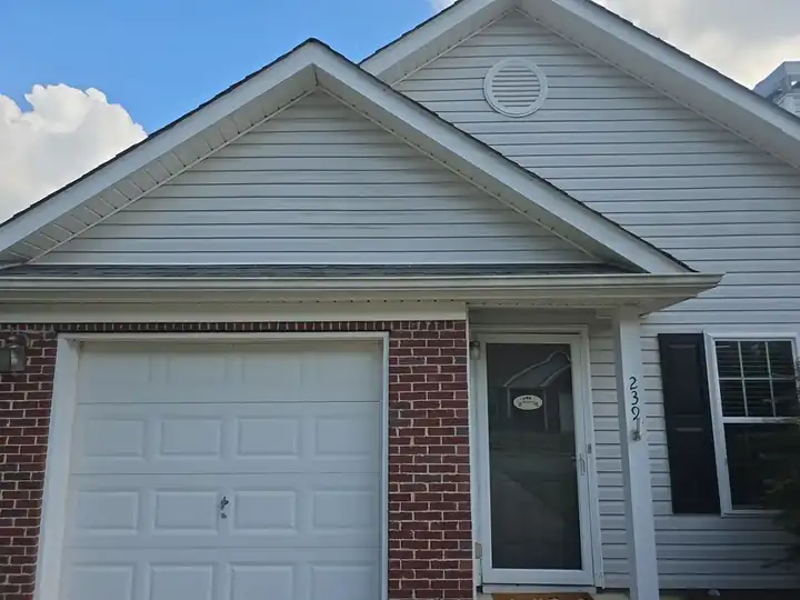Front facade of a residential home with vinyl siding, brick accents, and a white garage door in Woodstock, GA.