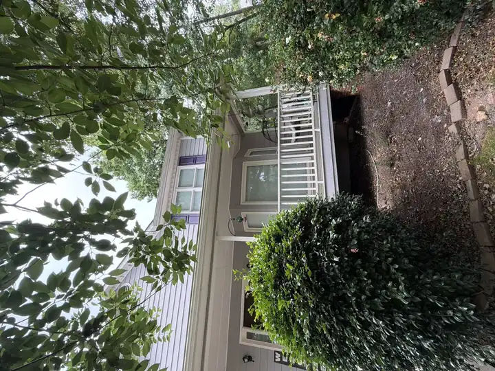 Full front view of two-story Canton, GA home with clean gray vinyl siding and white porch railing after house washing