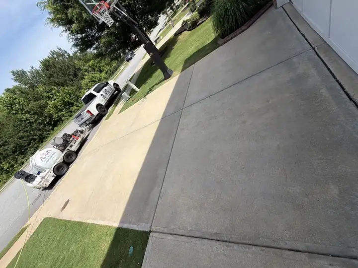 Concrete driveway after pressure washing in Canton, GA with Alpha Pressure Washing service truck parked at the street