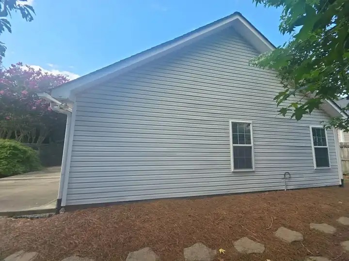 Side gable of a residential home showing vinyl siding and white gutters at a house wash job in Woodstock, GA.