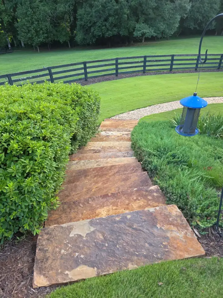 Flagstone garden path flanked by trimmed hedges at a residential property in Milton, GA.