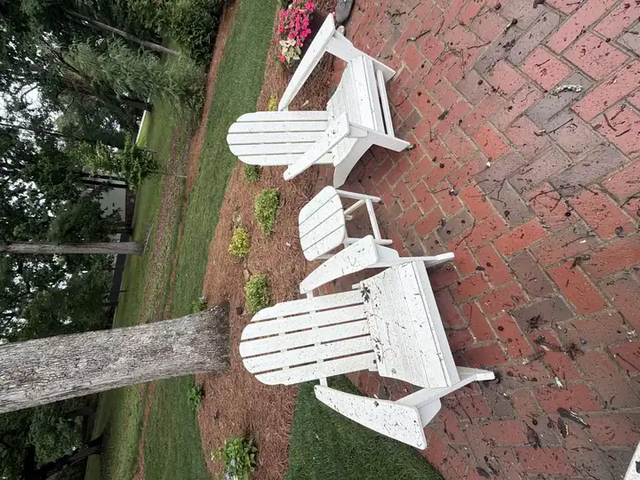 White Adirondack chairs on brick patio covered in leaf debris and grime before cleaning in Marietta, GA