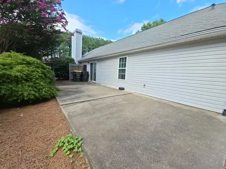 Wide view of a concrete patio alongside a residential home in Woodstock, GA after pressure washing.