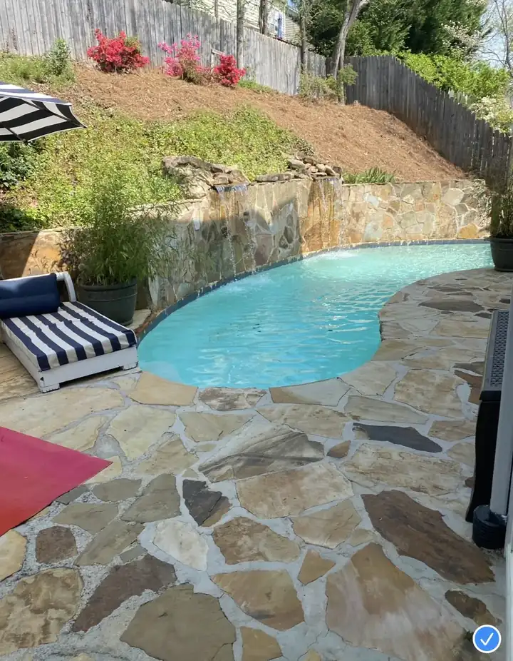 Pressure-washed flagstone pool deck in Alpharetta, GA showing clean stone pavers beside a kidney-shaped pool with waterfall feature