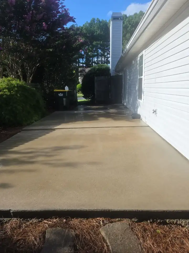 Side concrete driveway running along a residential home in Woodstock, GA, still wet after pressure washing.