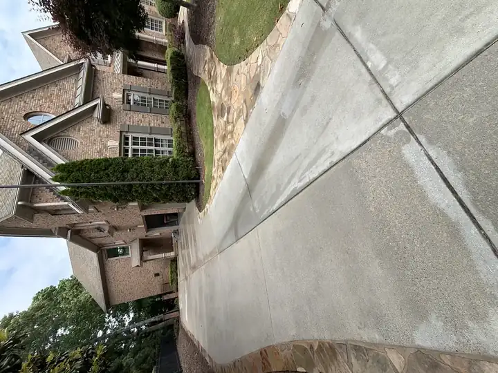 Wide-angle view of a concrete driveway with flagstone border at a two-story brick home in Duluth, GA.