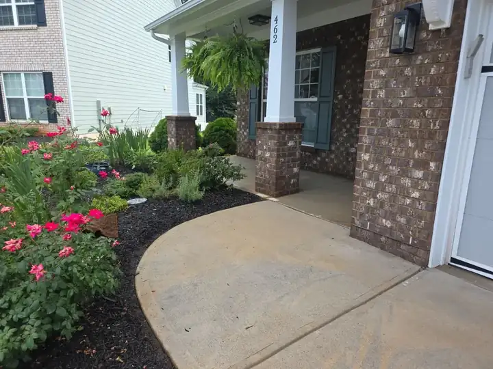 Curved concrete front walkway with garden beds and brick porch columns at a house washing job in Canton, GA.