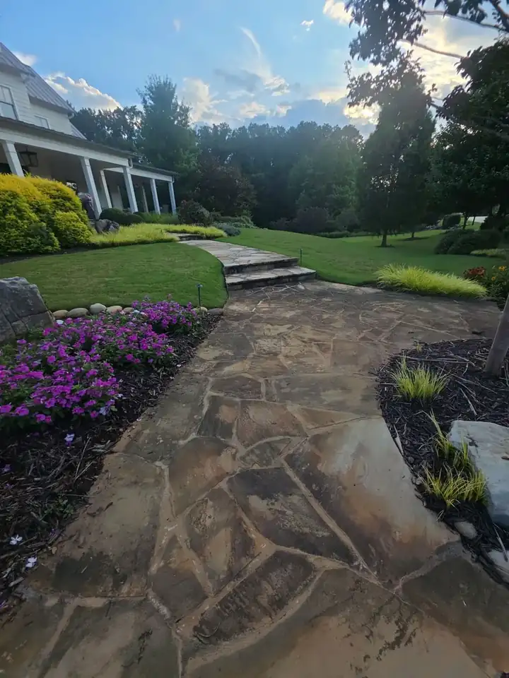 Flagstone front walkway with stone steps leading to the porch of a white farmhouse in Milton, GA.