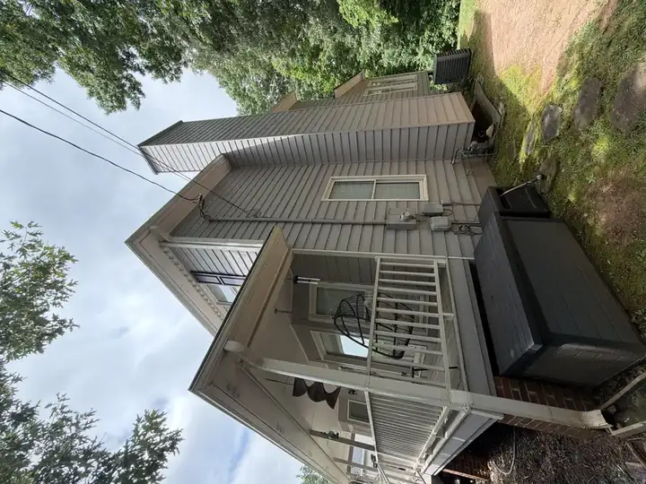 Side exterior of Canton, GA home with clean gray vinyl siding, porch, and chimney after house washing service