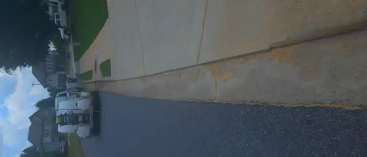 Concrete curb and sidewalk with rust and dirt staining at a pressure washing job in Canton, GA.