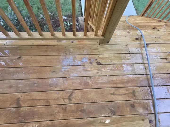 Close-up of a wet wood deck with pressure washing hose during a new construction wash in Atlanta, GA.
