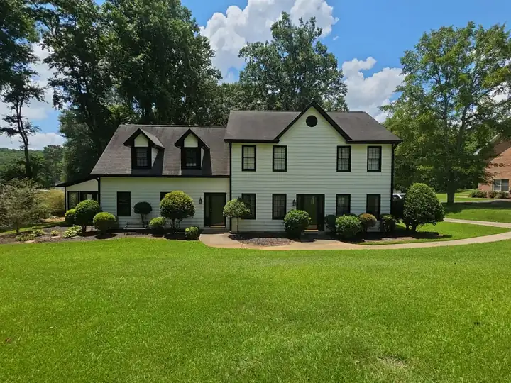 Full front view of a two-story white vinyl-sided home with circular driveway in Canton, GA after house washing.