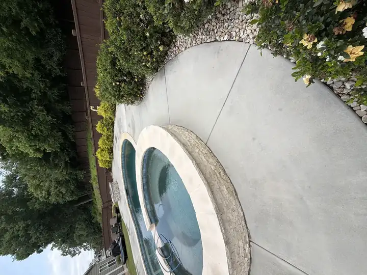 Freshly pressure-washed concrete pool deck wrapping around elevated spa in Canton, GA backyard