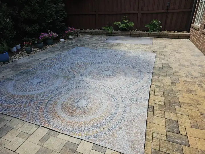 Stone paver patio with an outdoor rug, potted flowers, and wood fence at a pressure washing job in Marietta, GA.