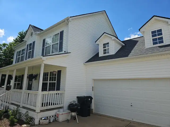 Side-angle view of a two-story home showing white vinyl siding, covered porch, and attached garage in Canton, GA.