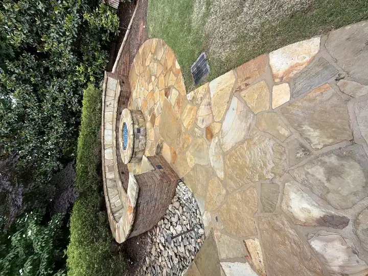 Flagstone patio with a circular fire pit and curved stone bench wall at a Duluth, GA residential pressure washing job.