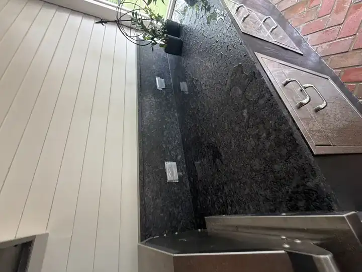 Clean dark granite outdoor kitchen counter and cabinetry after pressure washing service in Marietta, GA