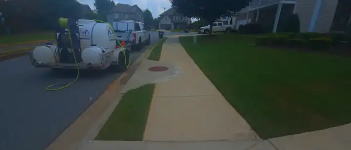 Pressure washing truck and trailer parked beside a concrete sidewalk and curb during a cleaning job in Canton, GA.