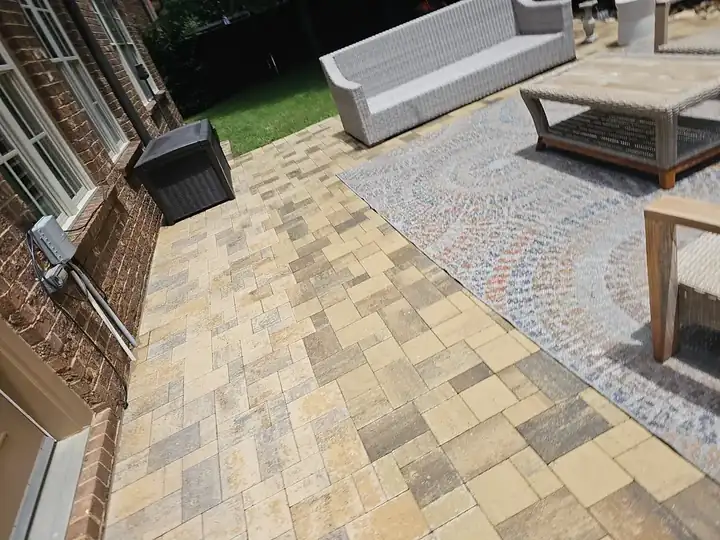 Close view of a multi-tone brick paver patio surface with wicker furniture visible at a Marietta, GA home.