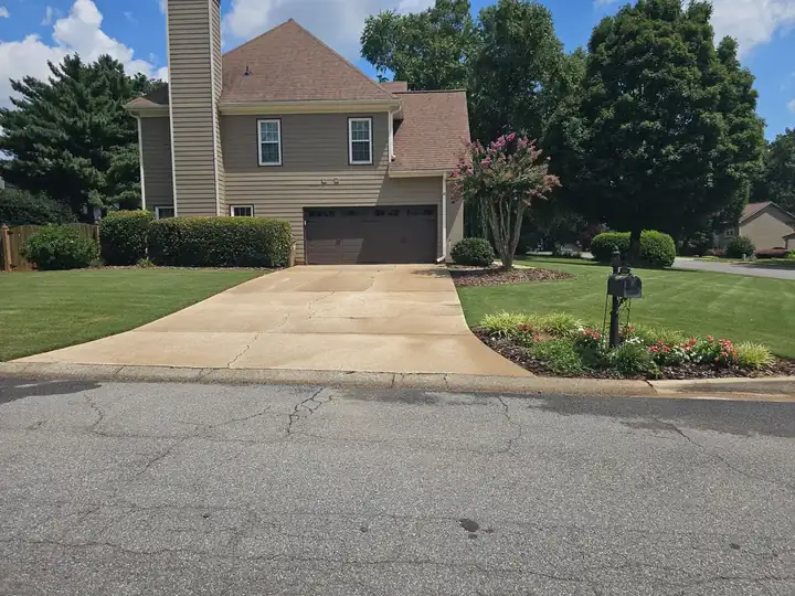 Concrete driveway at a residential home in Alpharetta, GA after pressure washing, viewed from the street with landscaping in foreground.