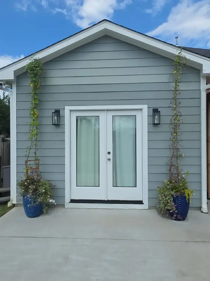 Rear gable of a gray vinyl-sided home with French doors and potted vines at a house washing job in Canton, GA.