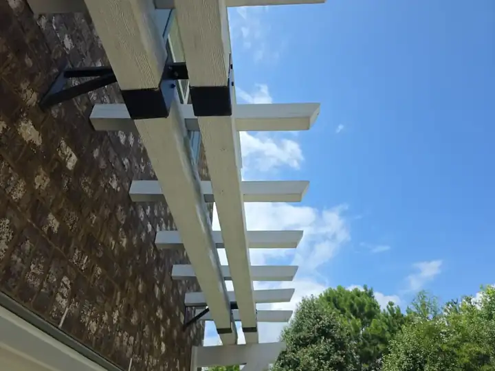 Low-angle view of a white wood pergola attached to a brick home at a pressure washing job in Canton, GA.