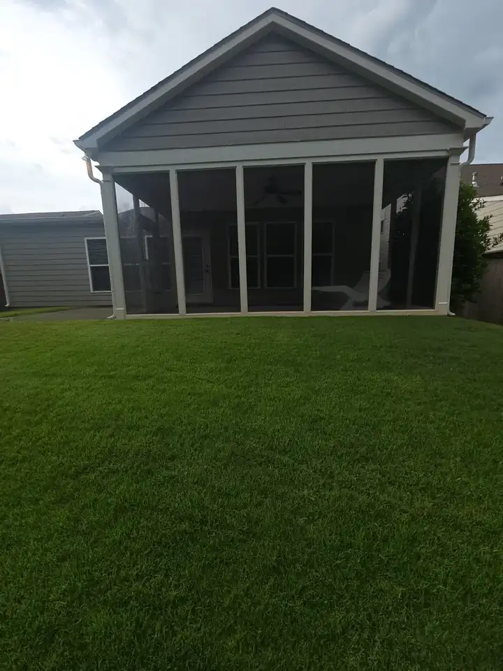 Exterior view of screened porch and vinyl siding after house washing in Woodstock, GA, backyard lawn clean and well-kept