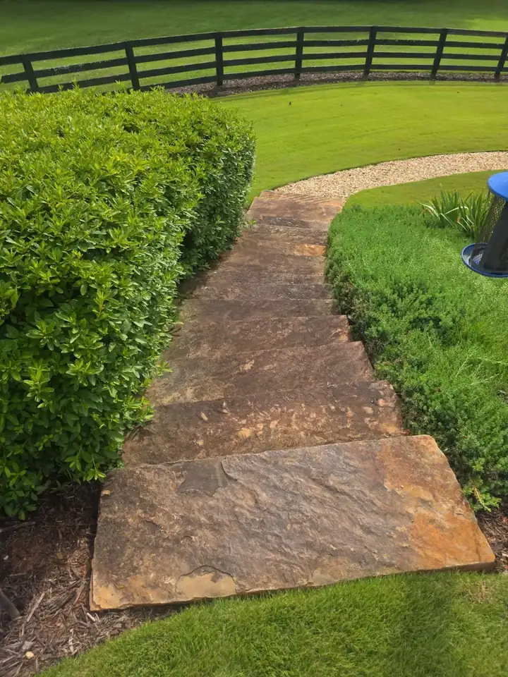 Flagstone garden path flanked by hedges and lawn at a residential property in Milton, GA.